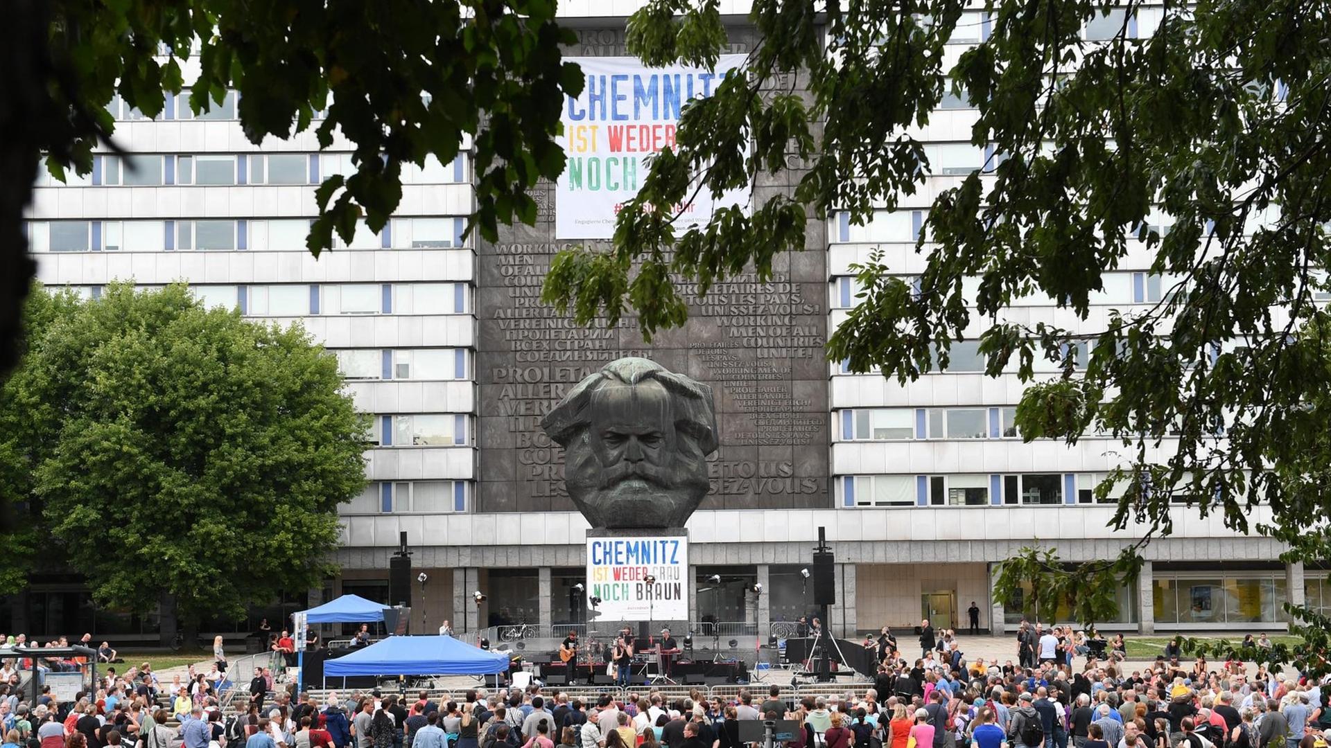 Zuschauer verfolgen vor dem Karl-Marx-Monument im Zentrum von Chemnitz ein Konzert verschiedener Bands unter dem Motto "#wirsindmehr".