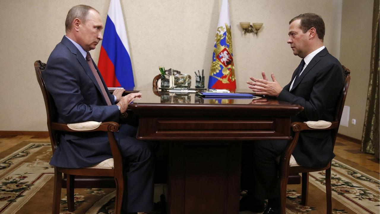 Russlands Präsident Wladimir Putin (links) und Ministerpräsident Dimitri Medwedew sitzen sich in Sewastopol an einem Tisch gegenüber.