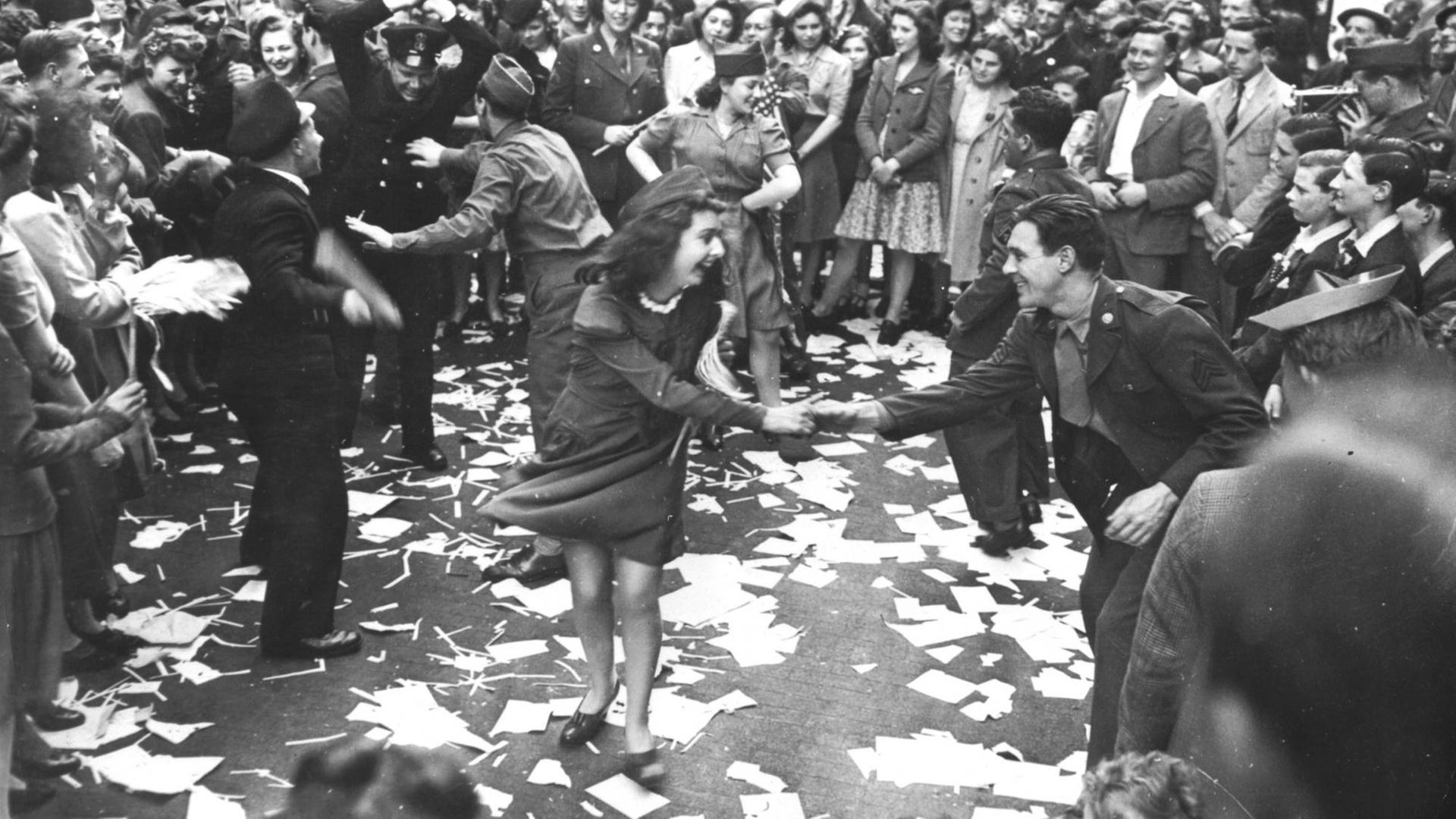 Britische Frauen tanzen mit amerikanischen Soldaten auf der Straße.