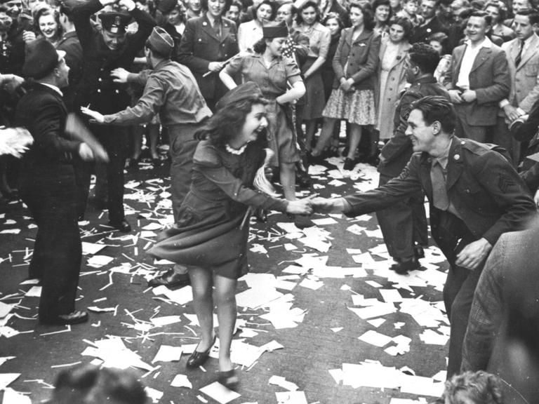 Britische Frauen tanzen mit amerikanischen Soldaten auf der Straße.