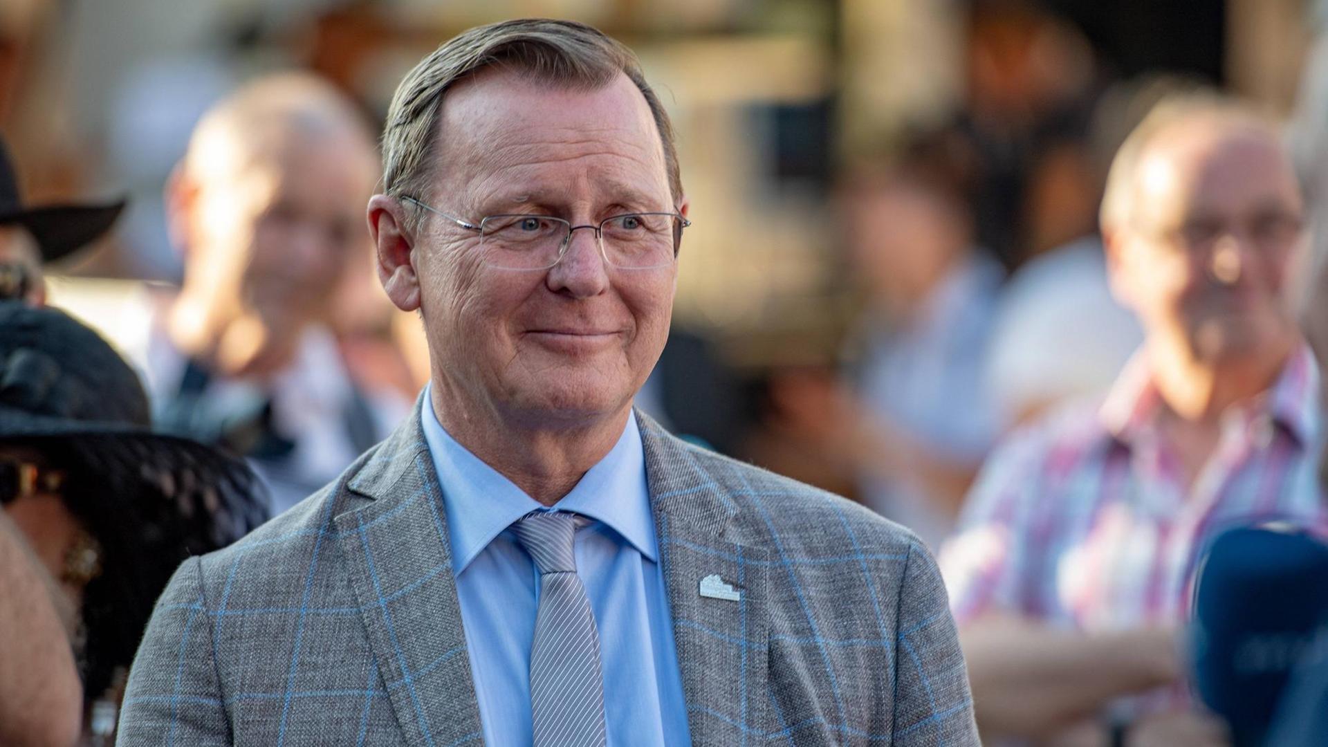 Bodo Ramelow steht in einer Menschenmenge und lächelt. Bodo Ramelow steht in einer Menschenmenge und lächelt.