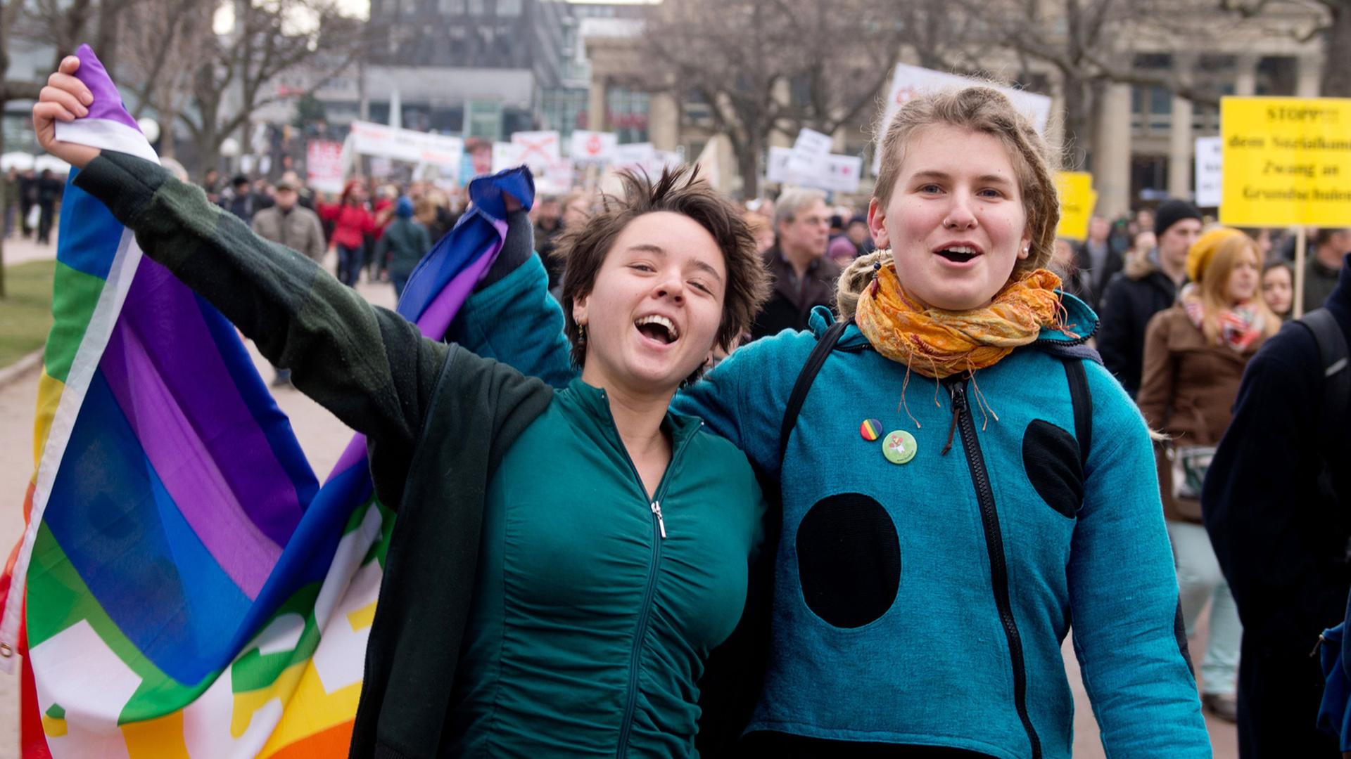 Zwei Befürworter der Aufwertung des Themas Homosexualität im Schulunterricht in Baden-Württemberg gehen am 01.02.2014 bei einer Demonstration in Stuttgart (Baden-Württemberg) über den Schlossplatz, in der Hand eine Regenbogenfahne. Zwei Befürworter der Aufwertung des Themas Homosexualität im Schulunterricht in Baden-Württemberg gehen am 01.02.2014 bei einer Demonstration in Stuttgart (Baden-Württemberg) über den Schlossplatz, in der Hand eine Regenbogenfahne.