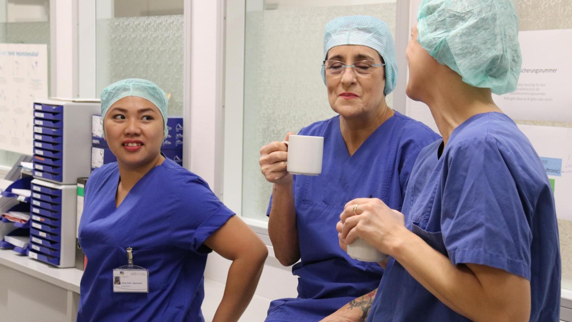 Daisy Agravante in Arbeitskleidung mit Kolleginnen bei der Teambesprechung im Uni-Klinikum. Daisy Agravante in Arbeitskleidung mit Kolleginnen bei der Teambesprechung im Uni-Klinikum.