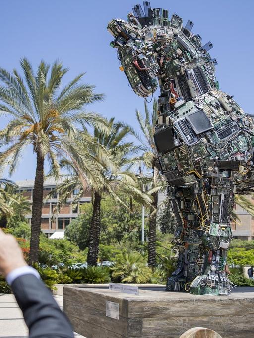 Ein Mann fotografiert die Skulptur eines Trojanischen Pferdes, zusammengesetzt aus mit Malware infizierten Computerteilen.