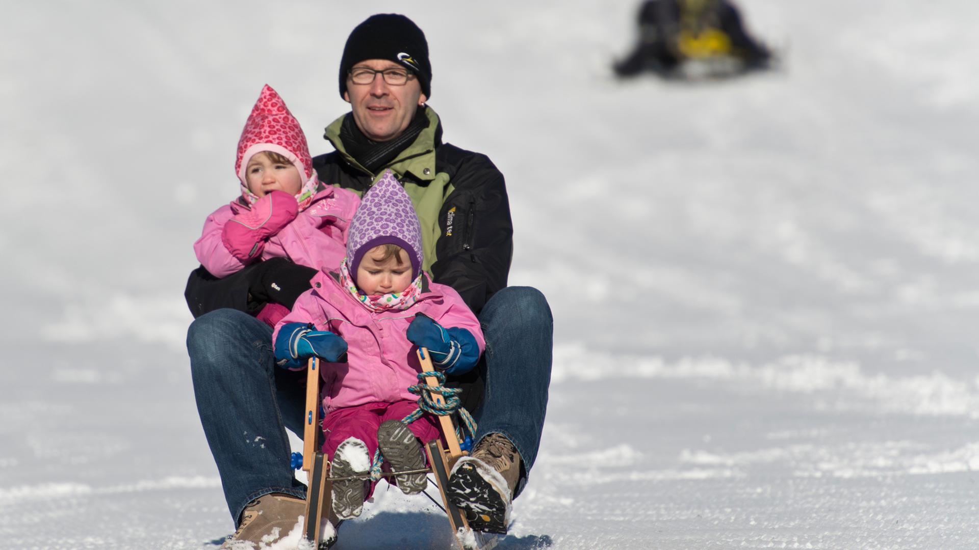 Ein Vater fährt auf dem Schauinsland bei Hofsgrund (Baden-Württemberg) mit den Zwilllingen Sophia und Ann auf dem Schlitten durch den Schnee. Ein Vater fährt auf dem Schauinsland bei Hofsgrund (Baden-Württemberg) mit den Zwilllingen Sophia und Ann auf dem Schlitten durch den Schnee.