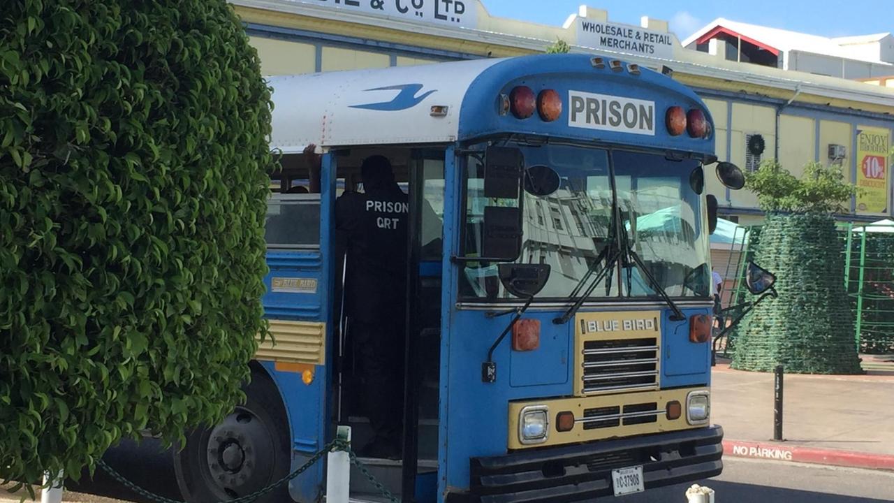 Ein blauer Autobus hält auf einer Straße zwischen grünen Büschen. Ein blauer Autobus hält auf einer Straße zwischen grünen Büschen.