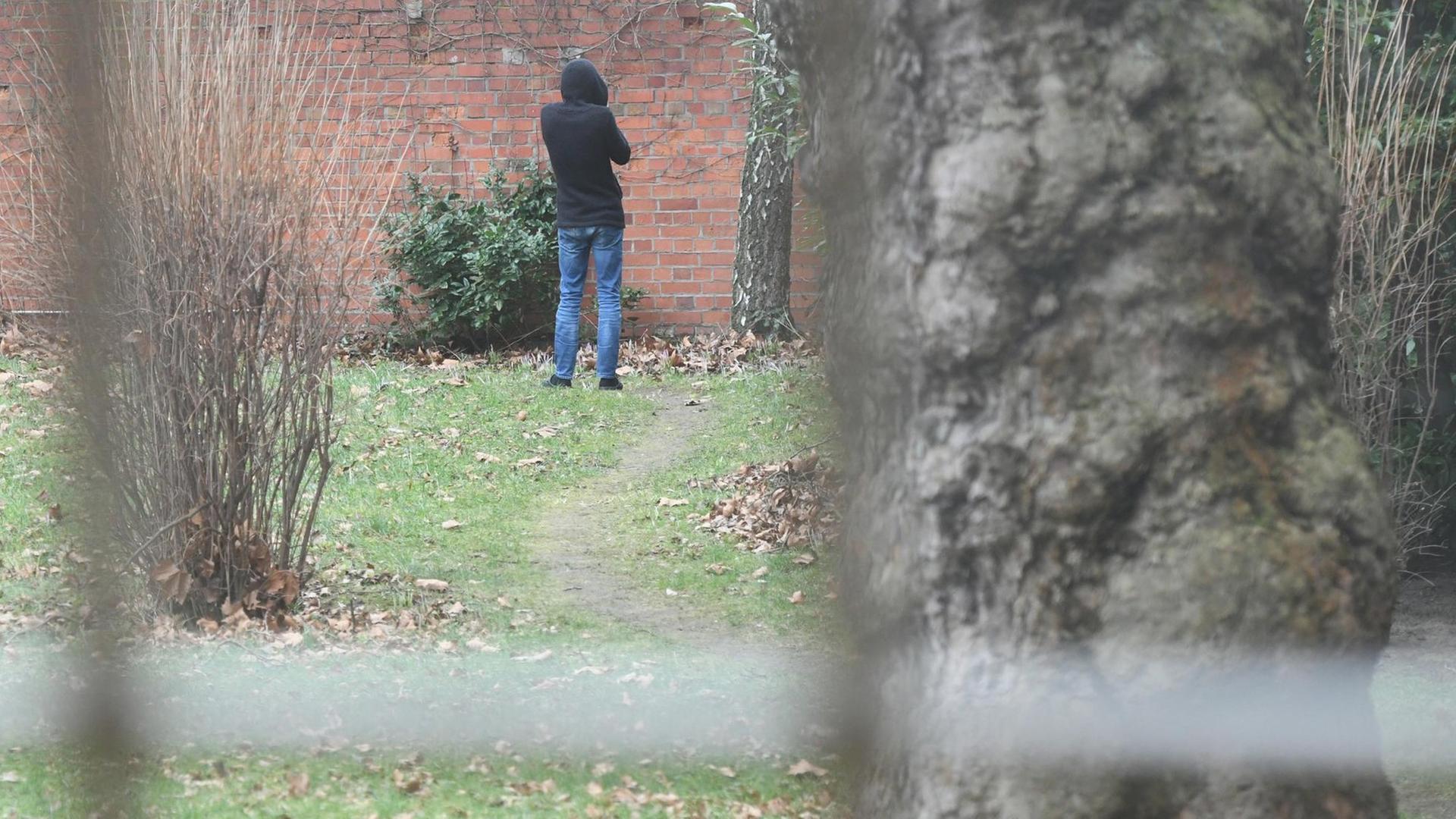 30.01.2018, Berlin: Die Charité-Klinik für Psychiatrie und Psychotherapie. Eine Person mit Kaputzenpulli steht vor einer Mauer in einem Garten. 30.01.2018, Berlin: Die Charité-Klinik für Psychiatrie und Psychotherapie. Eine Person mit Kaputzenpulli steht vor einer Mauer in einem Garten.