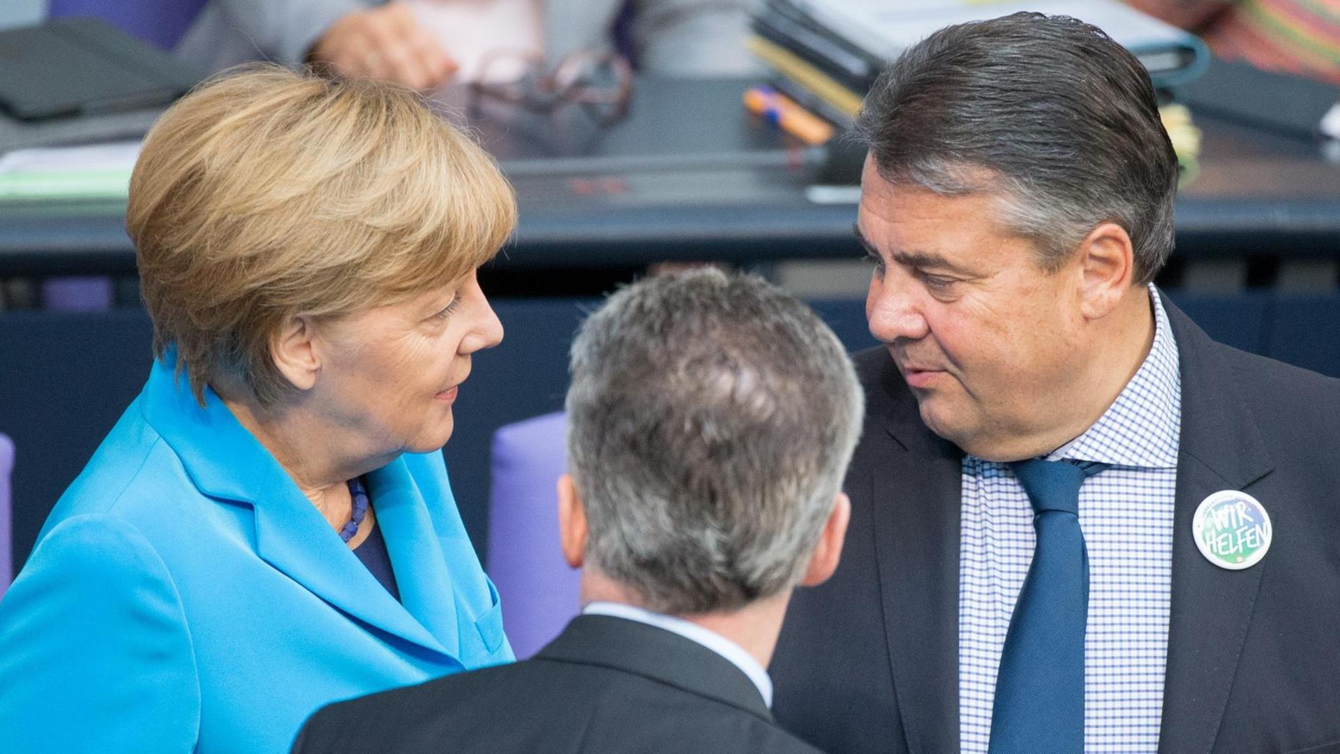Bundeskanzlerin Angela Merkel (vl, CDU), Bundesinnenminister Thomas de Maiziere (CDU) und Bundeswirtschaftsminister Sigmar Gabriel (SPD) unterhalten sich am 09.09.2015 im Bundestag in Berlin.
