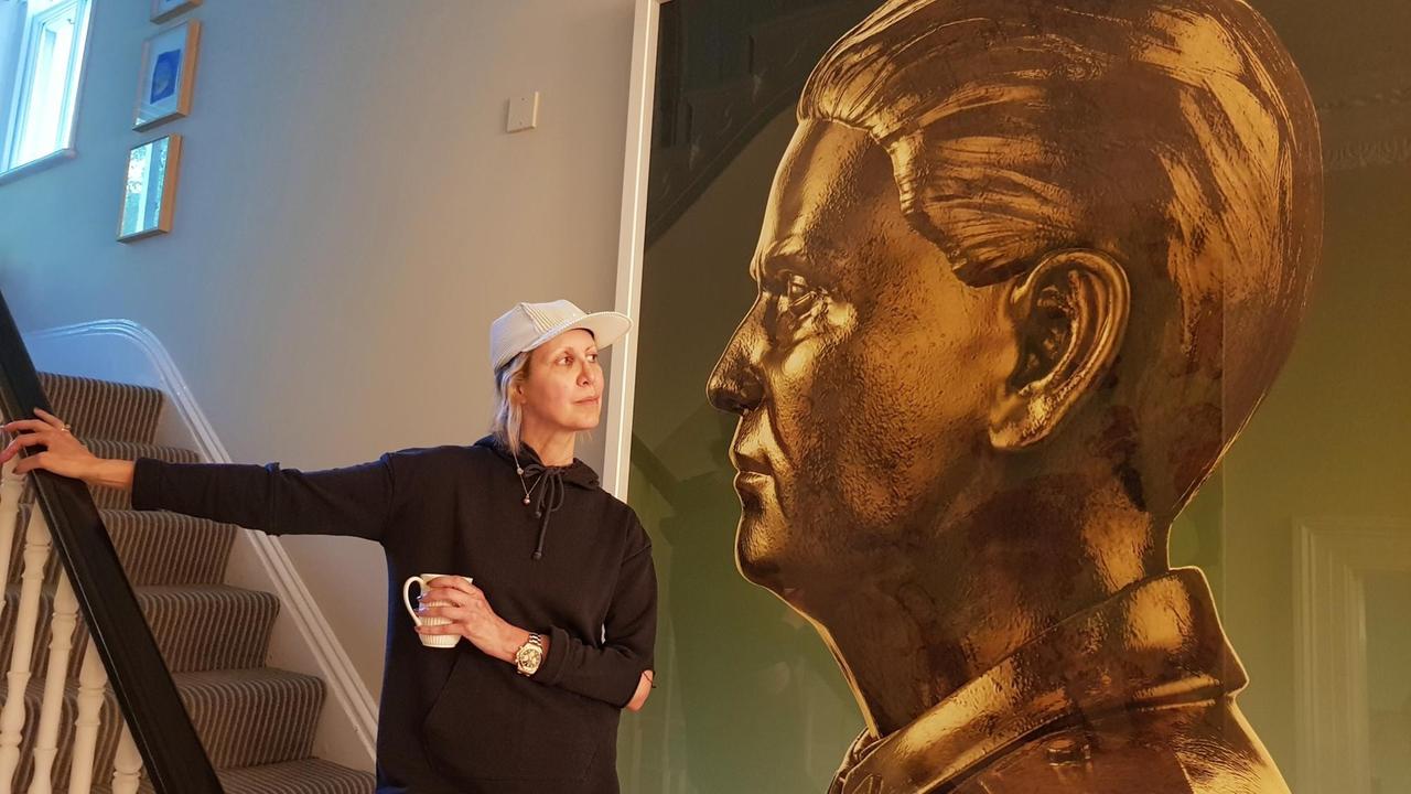 Die Kunstsammlerin Valeria Napoleone steht in ihrer Londoner Wohnung auf der Treppe und blickt auf ein mehrere Meter hohes Bild eines vergoldeten Mannes. 