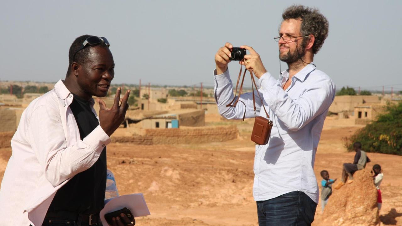 Der Regisseur Christoph Schlingensief (r) fotografiert in Burkina Faso neben Francis Kere, dem Architekten des "Operndorfes".