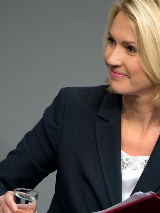 Die Bundesministerin für Familie, Frauen, Jugend und Senioren, Manuela Schwesig (SPD), hält am 06.03.2015 in Berlin während der Sitzung des Bundestages nach ihrer Rede lächelnd ein Glas in der Hand.