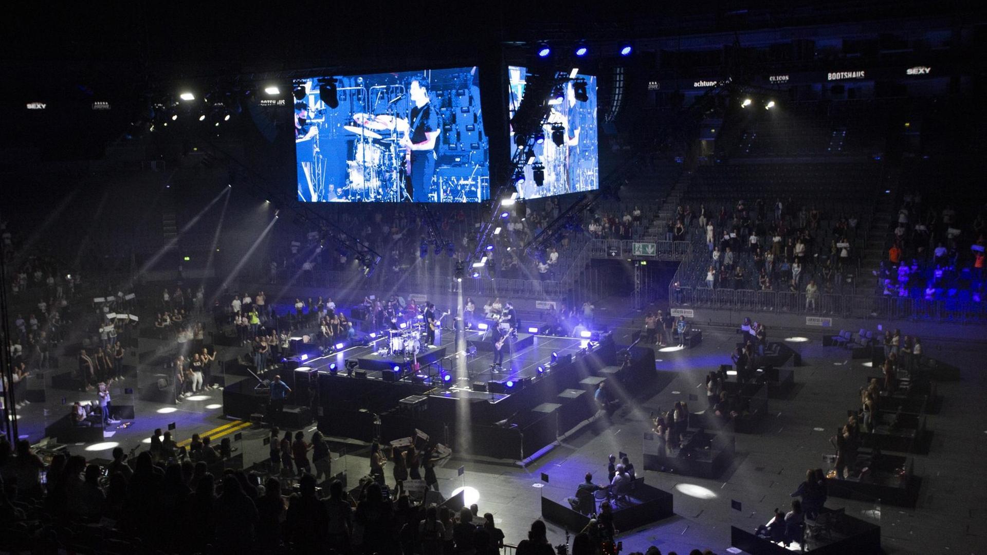 Blick in die Lanxess-Arena in Köln am 20.06.2020: Sänger Wincent Weiss steht mit seiner Band in der Mitte auf einem Podest. Zuschauer sitzen oder stehen in zur Bühne hin geöffneten Plexiglasboxen.