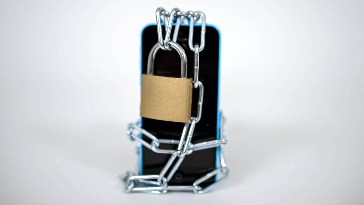 Ein handy ist mit einem Schloss gesichert und kann nicht genutzt werden. Ein handy ist mit einem Schloss gesichert und kann nicht genutzt werden.