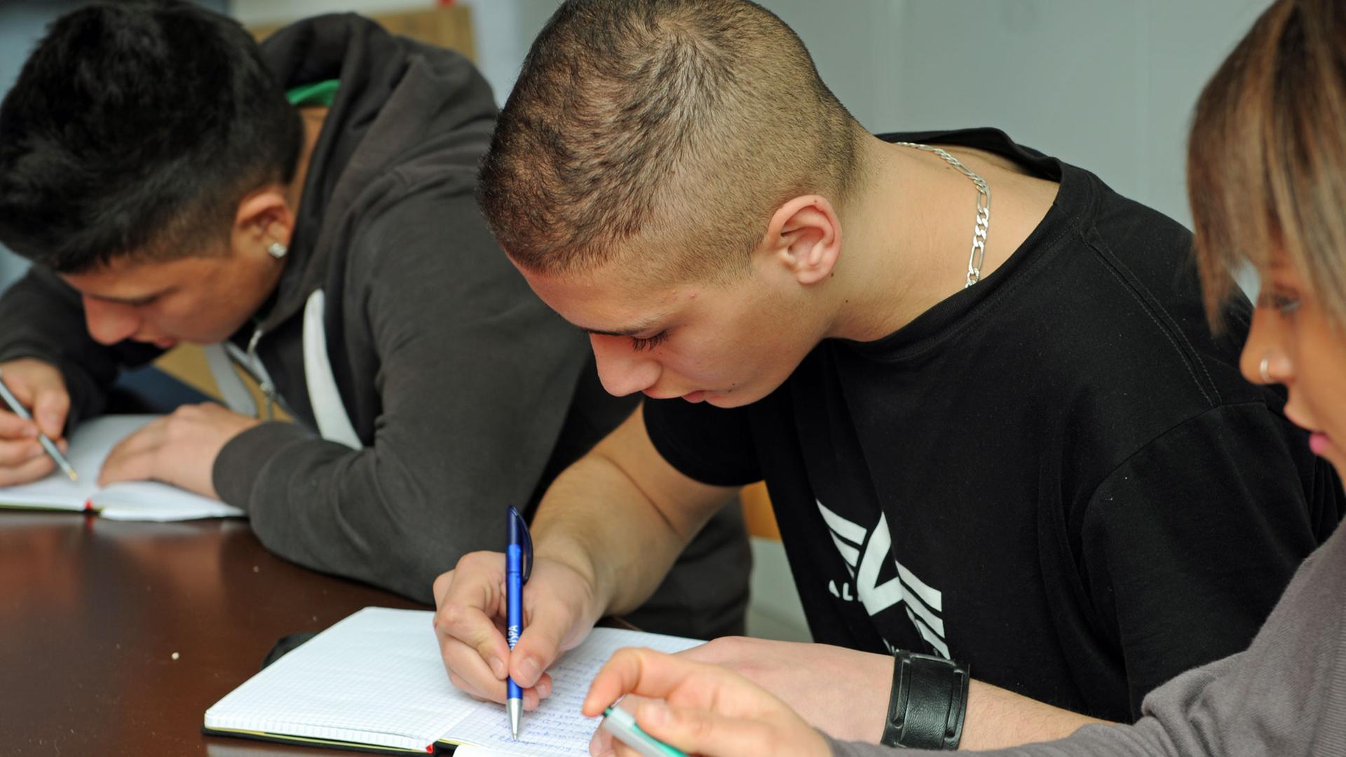 Zwei Jungen sitzen in der Schulbank und schreiben mit gesenkten Köpfen in Tagebücher. Zwei Jungen sitzen in der Schulbank und schreiben mit gesenkten Köpfen in Tagebücher.