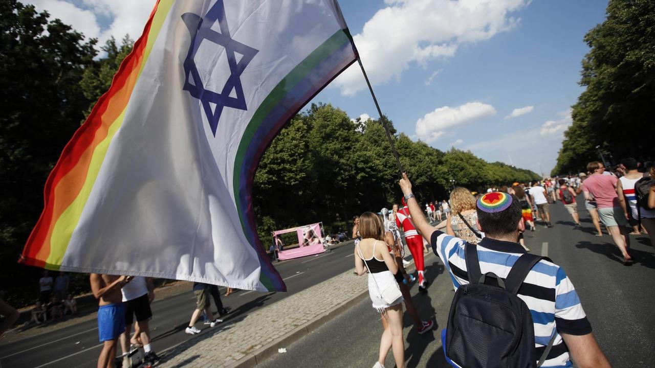 Jüdischer Teilnehmer auf dem CSD-Berlin mit regenbogenfarbener Kippa und Fahne Jüdischer Teilnehmer auf dem CSD-Berlin mit regenbogenfarbener Kippa und Fahne