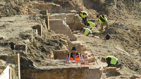 Archäologen arbeiten zwischen alten Mauern und Siedlungsresten.