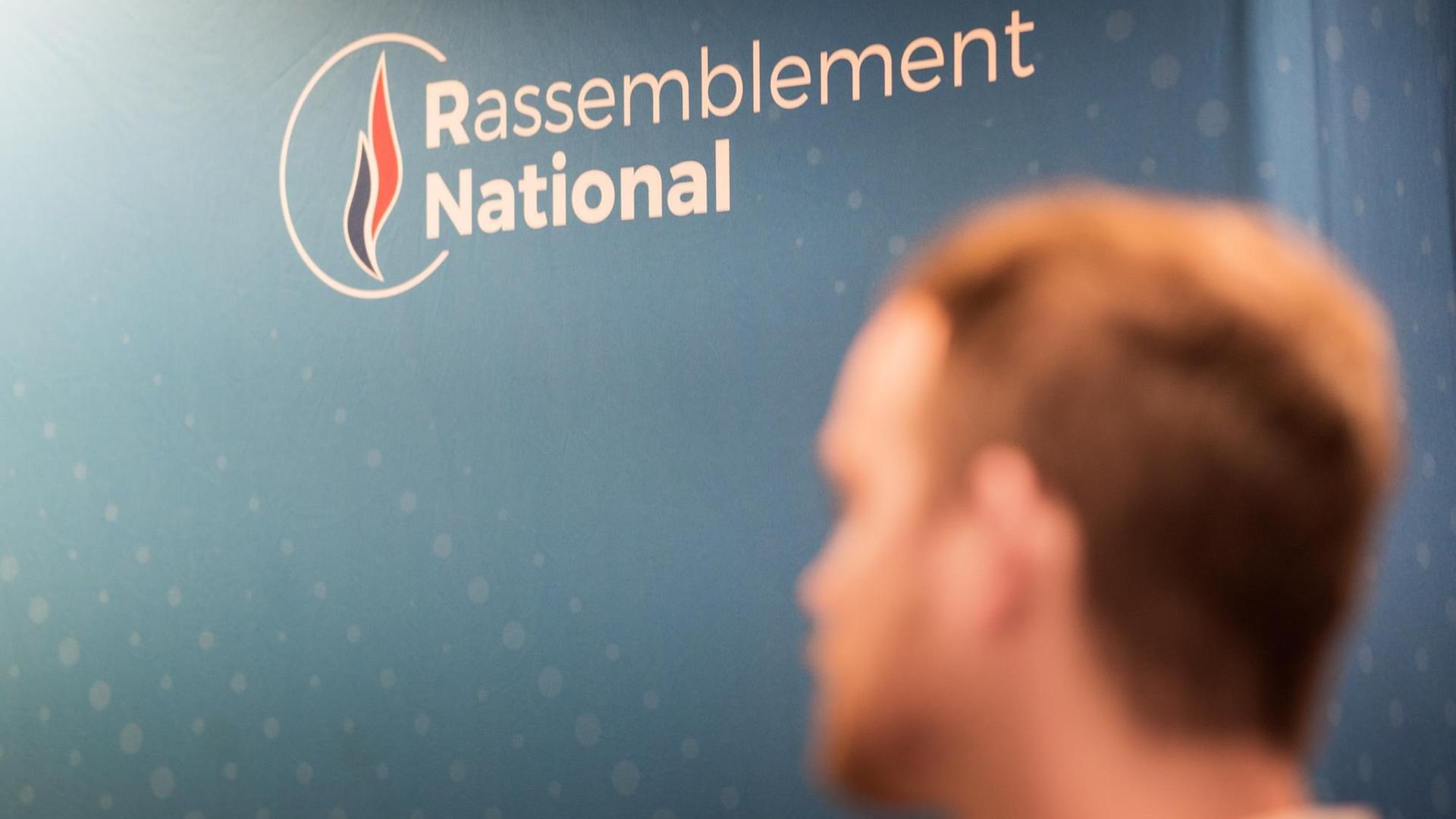 Ein unscharfer männlicher Kopf steht vor einem Plakat, Rassenblément National. Ein unscharfer männlicher Kopf steht vor einem Plakat, Rassenblément National.