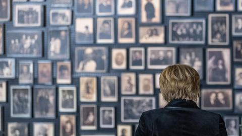 Eine Frau steht vor einer Wand mit vielen Bildern von Menschen.