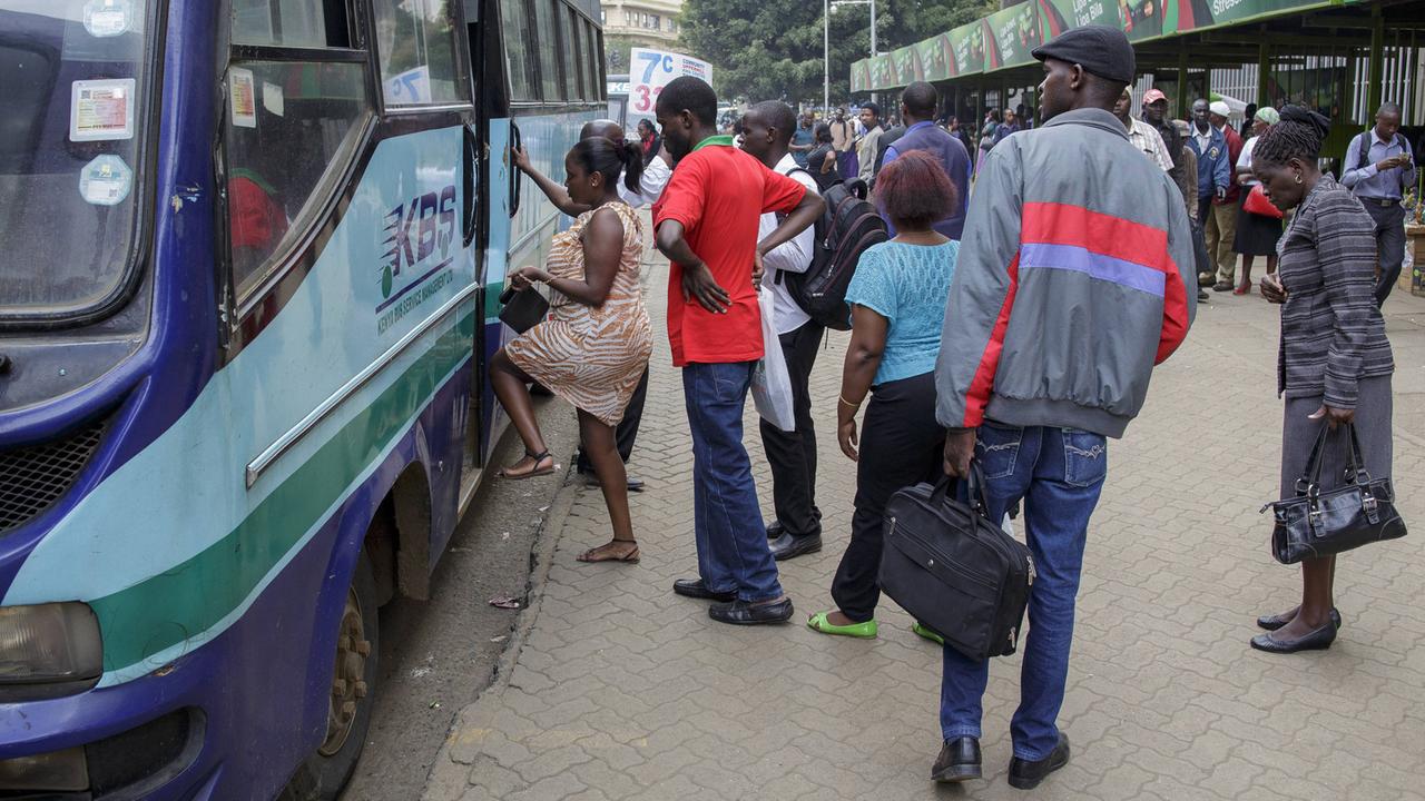 Fahrgäste steigen in einen Bus. Strassenszene in Nairobi, Hauptstadt von Kenia.