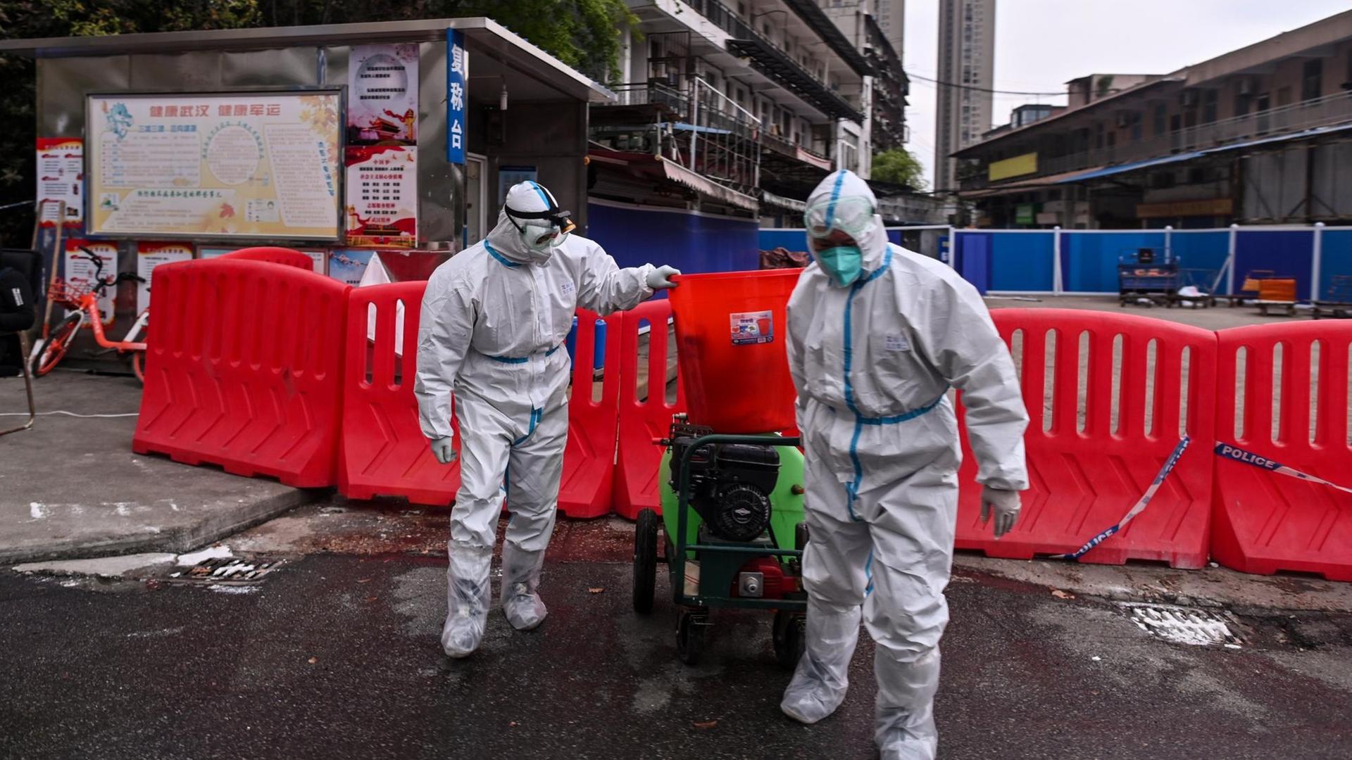 Das Foto vom 30. März 2020 zeigt Arbeiter in Schutzanzügen vor dem abgeriegelten Meeresfrüchte-Großmarkt in Wuhan in der zentralchinesischen Provinz Hubei. Das Foto vom 30. März 2020 zeigt Arbeiter in Schutzanzügen vor dem abgeriegelten Meeresfrüchte-Großmarkt in Wuhan in der zentralchinesischen Provinz Hubei.