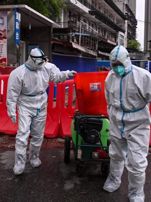 Das Foto vom 30. März 2020 zeigt Arbeiter in Schutzanzügen vor dem abgeriegelten Meeresfrüchte-Großmarkt in Wuhan in der zentralchinesischen Provinz Hubei.