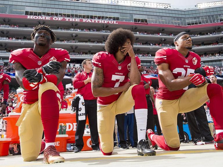 Colin Kaepernick (Mitte) kniet zusammen mit Eli Harold und Eric Reid vor einem Football-Spiel im Stadion am 2. Oktober 2016 in Santa Clara, Californien.