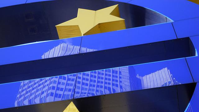 Das Gebäude der Europäischen Zentralbank (EZB) in Frankfurt am Main spiegelt sich im Eurozeichen-Kunstwerk des Künstlers Otmar Hoerl.