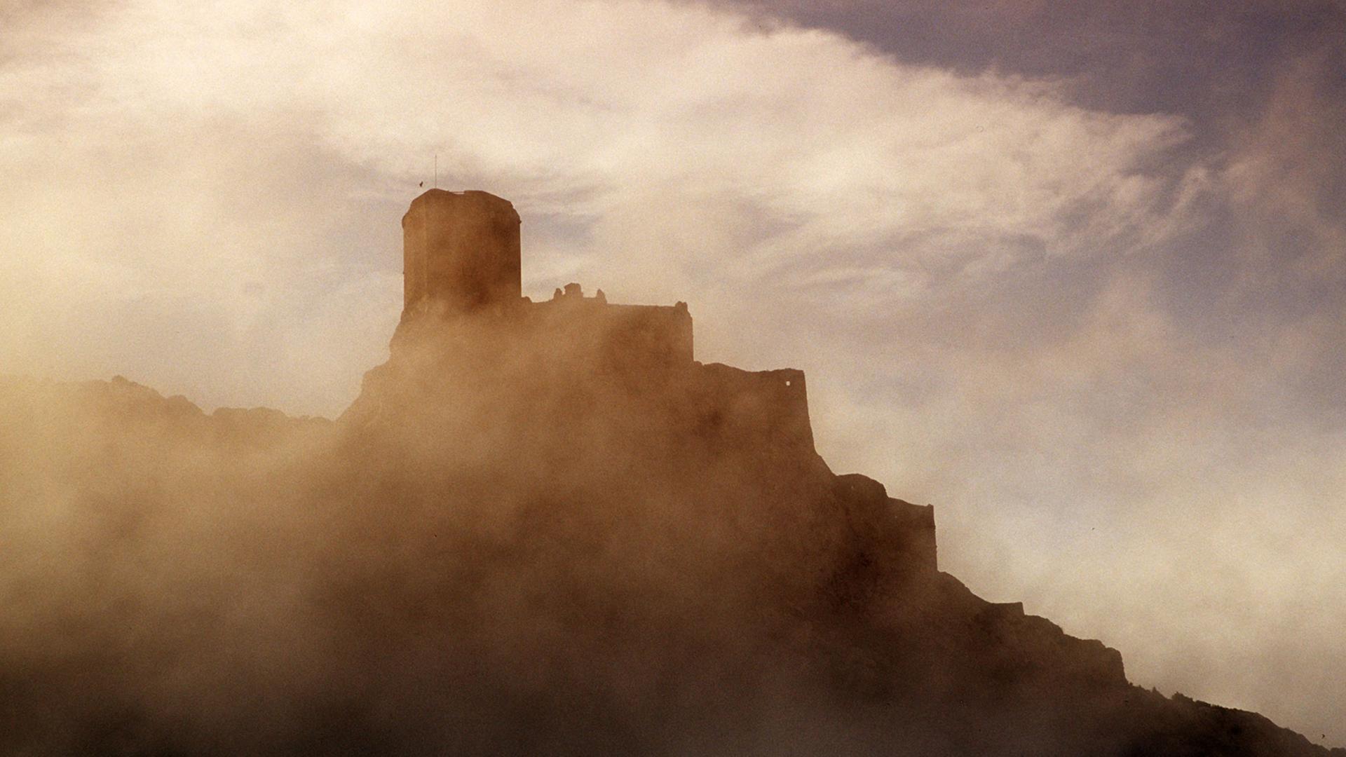 Wolkenfetzen verhüllen die historische Burgruine von Queribus, einstmals eine Burg der Katharer, aus dem 11. bis 12. Jahrhundert im Corbieres, einem Vorgebirge der Pyrenäen. Wolkenfetzen verhüllen die historische Burgruine von Queribus, einstmals eine Burg der Katharer, aus dem 11. bis 12. Jahrhundert im Corbieres, einem Vorgebirge der Pyrenäen.