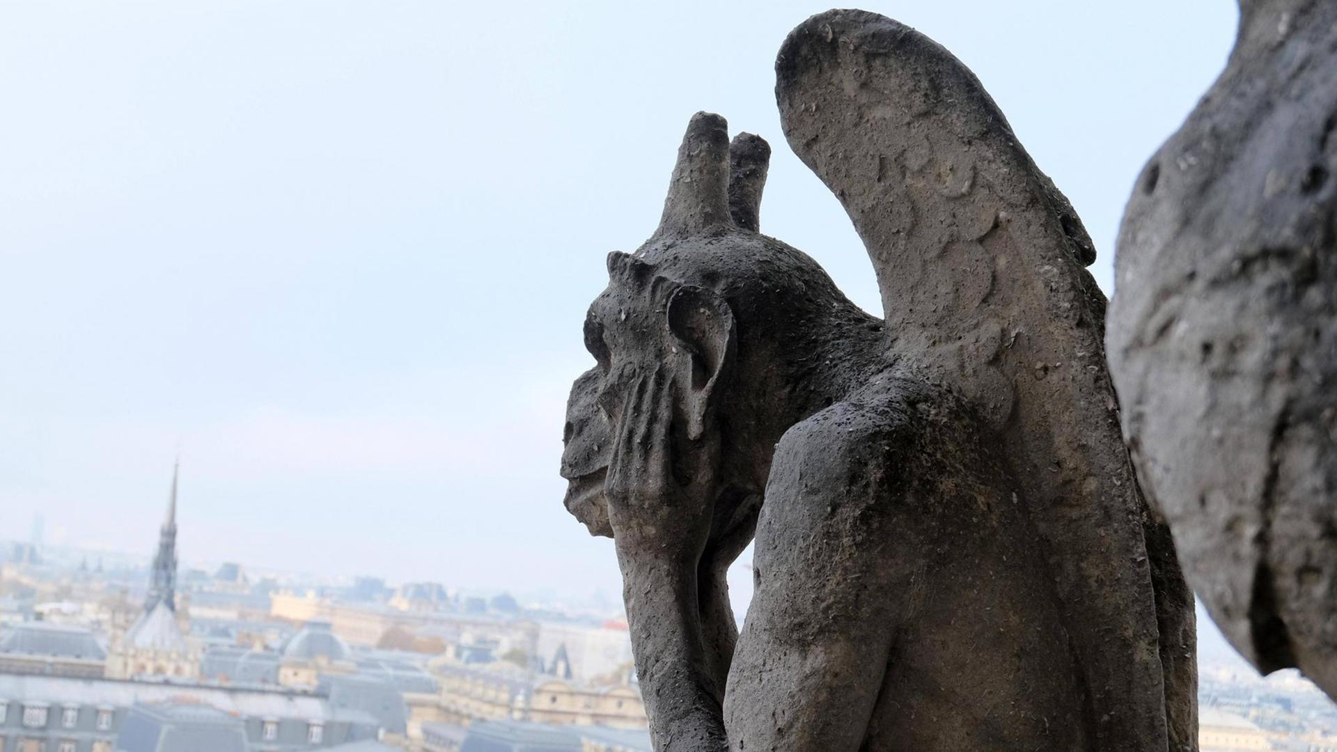 Eine Chimärenfigur an der Fassade von der Kathedrale in Notre-Dame guckt sorgend auf die Stadt. Eine Chimärenfigur an der Fassade von der Kathedrale in Notre-Dame guckt sorgend auf die Stadt.