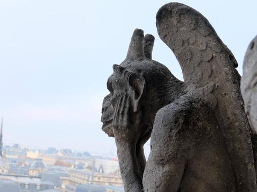 Eine Chimärenfigur an der Fassade von der Kathedrale in Notre-Dame guckt sorgend auf die Stadt.
