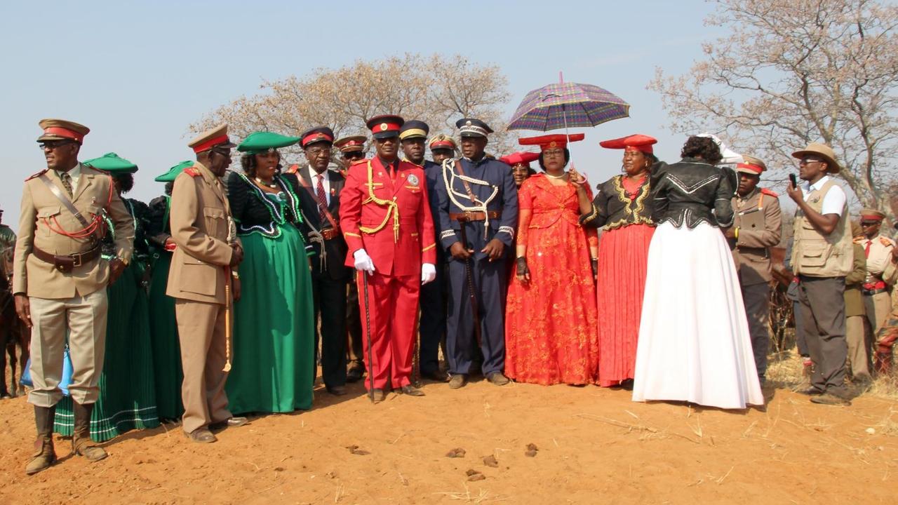 Stammesoberhaupt Chief Vekuii Rukoro (M, rote Uniform) und andere örtliche Stammesältere stehen auf dem Hügel, von dem aus der damalige deutsche Generalleutnant Lothar von Trotha den Schießbefehl gab, der den Beginn des Völkermordes an den Herero markierte. Stammesoberhaupt Chief Vekuii Rukoro (M, rote Uniform) und andere örtliche Stammesältere stehen auf dem Hügel, von dem aus der damalige deutsche Generalleutnant Lothar von Trotha den Schießbefehl gab, der den Beginn des Völkermordes an den Herero markierte.
