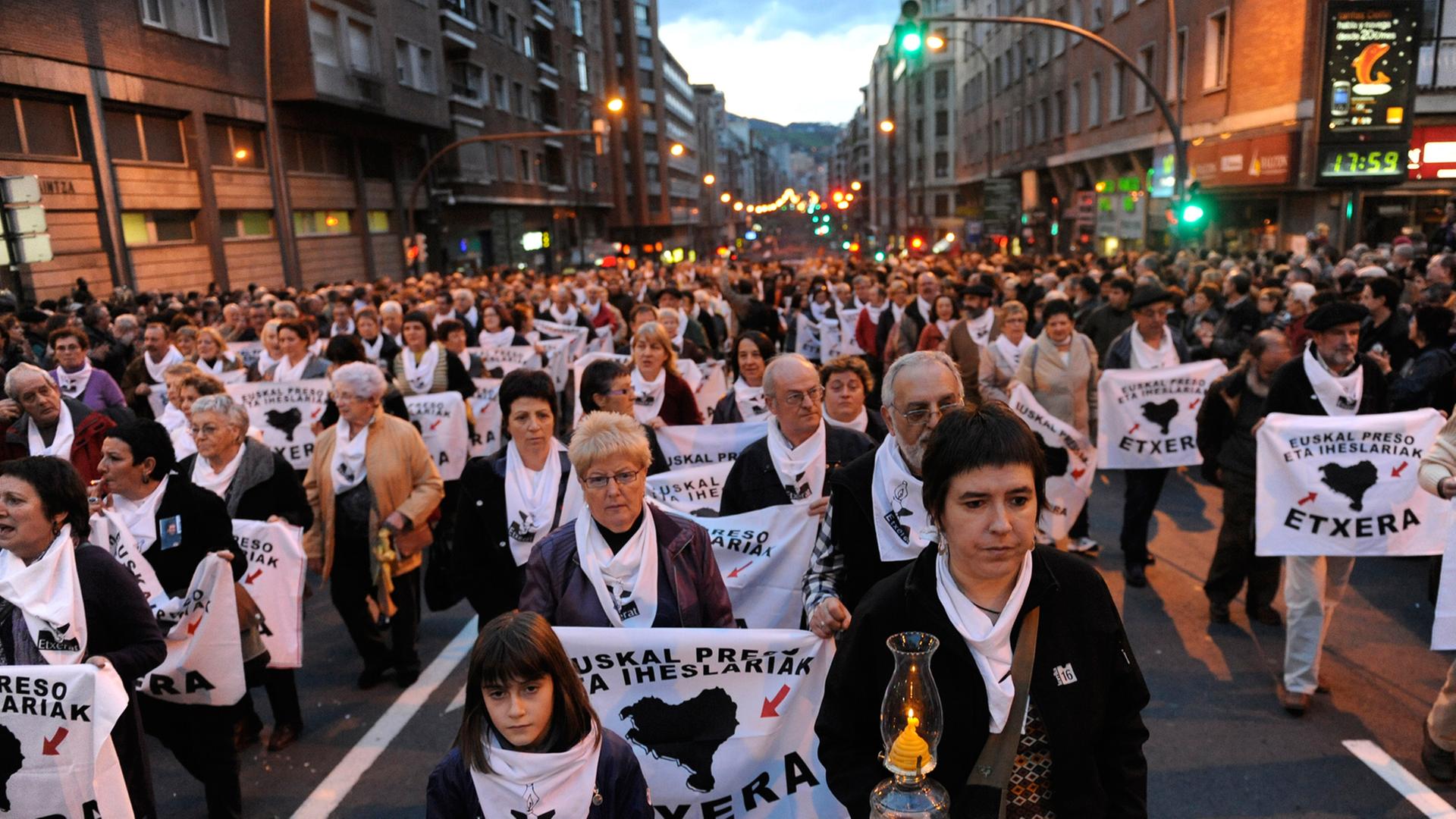 Demonstranten im Dunkeln auf einer Straße, die weiße Banner und Kerzen halten, auf den Bannern ist in baskisch zu lesen: "Mit allen Rechten. Baskische Häftlinge zurück ins Baskenland."