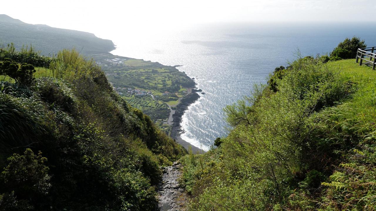 Zwischen zwei Bergen geht es durch eine grüne Landschaft steil hinunter zum Meer. Zwischen zwei Bergen geht es durch eine grüne Landschaft steil hinunter zum Meer.
