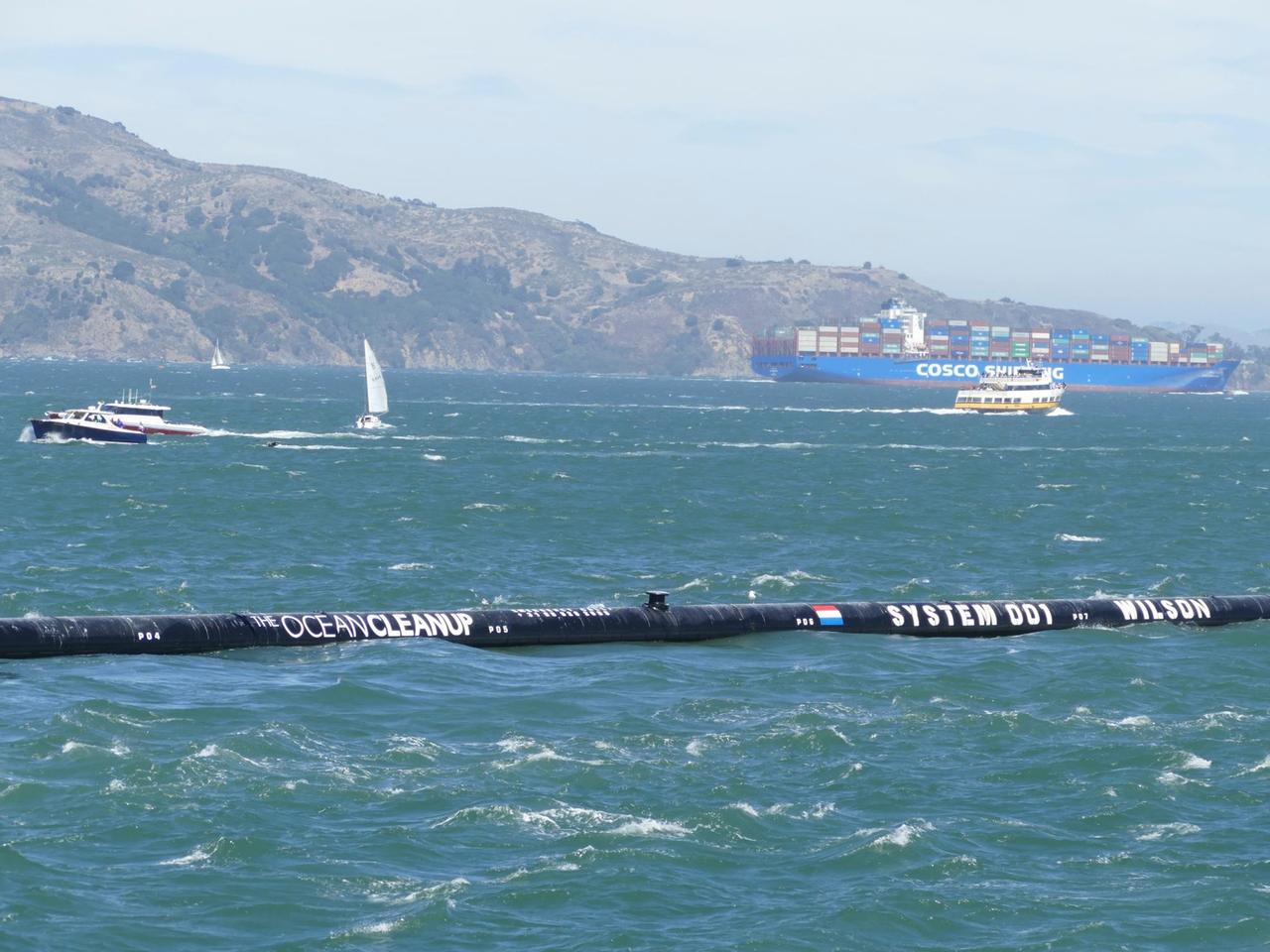 08.09.2018,USA, San Francisco: Das erste schwimmende Abfallsammelgerät "The Ocean Cleanup" ist auf seinem Weg zum Pazifischen Ozean in der Bucht von San Francisco zu sehen. Wie Fangarme sollen sich die Enden des 600 Meter langen Kunststoffrohrs des Reinigungssystems um Berge von Plastikmüll legen - zunächst auf dem Pazifik zwischen Kalifornien und Hawaii. Foto: Barbara Munker/dpa | Verwendung weltweit 08.09.2018,USA, San Francisco: Das erste schwimmende Abfallsammelgerät "The Ocean Cleanup" ist auf seinem Weg zum Pazifischen Ozean in der Bucht von San Francisco zu sehen. Wie Fangarme sollen sich die Enden des 600 Meter langen Kunststoffrohrs des Reinigungssystems um Berge von Plastikmüll legen - zunächst auf dem Pazifik zwischen Kalifornien und Hawaii. Foto: Barbara Munker/dpa | Verwendung weltweit