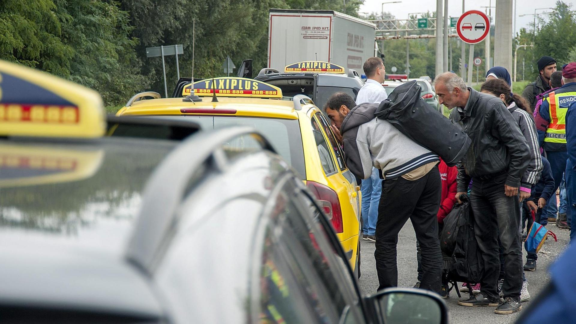 Flüchtlinge sprechen mit einem Taxifahrer in Vámosszabadi im Herbst 2015.