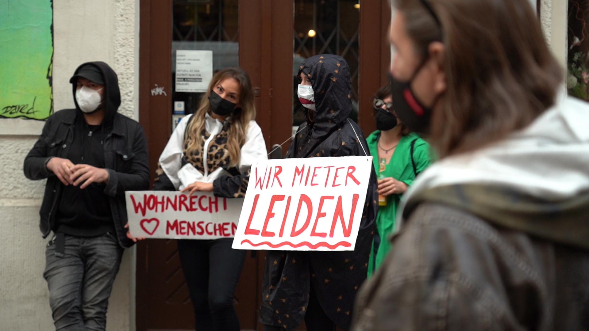 Mehrere Teilnehmer einer Demonstration gegen Wohnungsspekulation in Berlin mit Mund-Nase-Schutz und Plakaten.