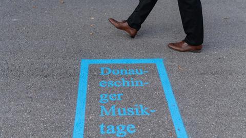 19.10.2018, Baden-Württemberg, Donaueschingen: Ein Mann läuft am Logo der Donaueschinger Musiktage vor der Donauhalle vorbei.