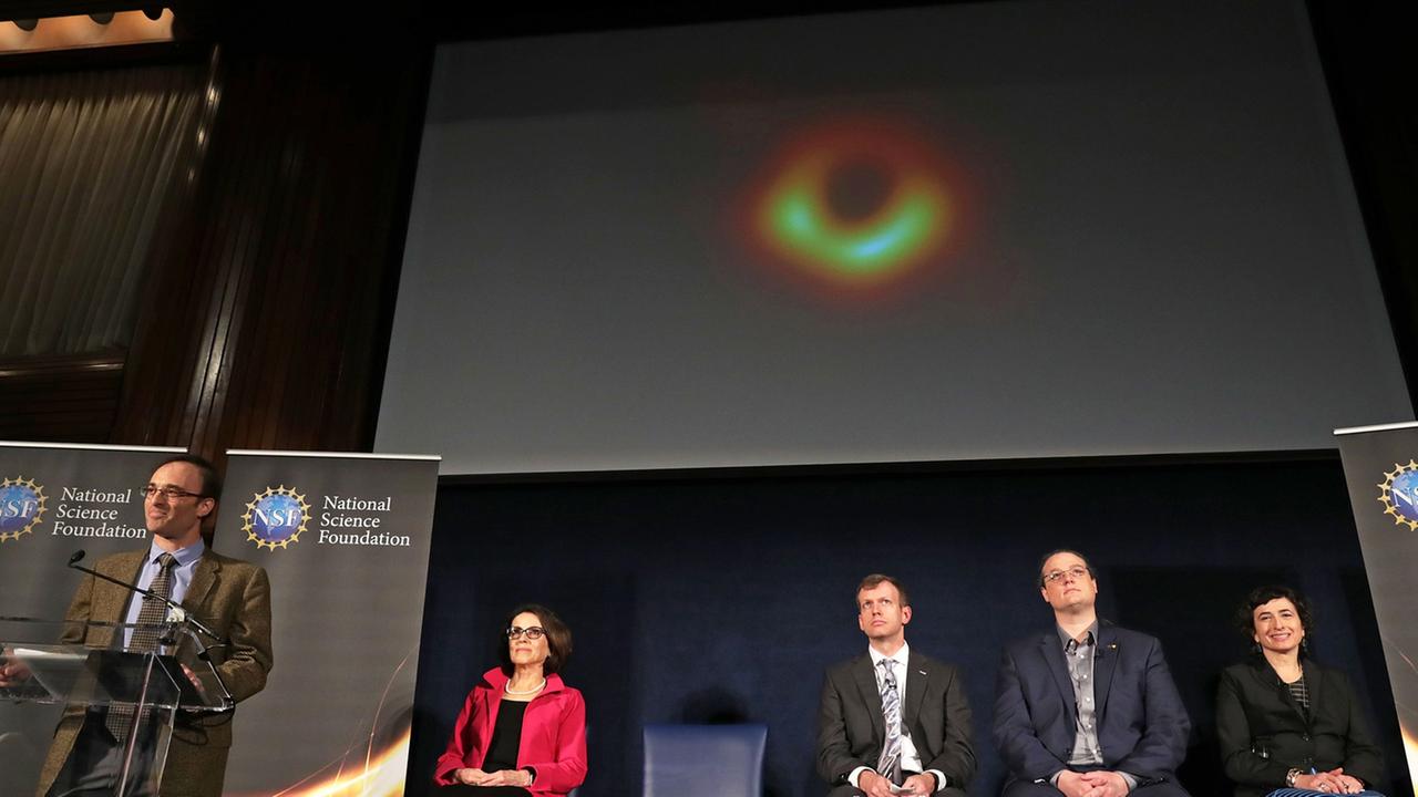 Bei der Präsentation der Aufnahme eines Schwarzen Lochs der National Science Foundation der USA in Washington sitzen mehere Personen auf dem Podium, ein Mann steht am Mikrofon und spricht. Personen: Sheperd Doeleman, France Cordova, Dan Marrone, Avery Broderick, Sera Markoff Bei der Präsentation der Aufnahme eines Schwarzen Lochs der National Science Foundation der USA in Washington sitzen mehere Personen auf dem Podium, ein Mann steht am Mikrofon und spricht. Personen: Sheperd Doeleman, France Cordova, Dan Marrone, Avery Broderick, Sera Markoff