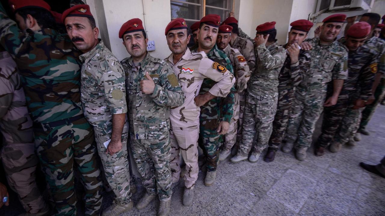 Irakische Soldaten und Sicherheitsbeamte stehen vor einem Wahllokal Schlange, um ihre Stimmen abzugeben. Polizei und Militär geben ihre Stimmen zwei Tage vor der eigentlichen Parlamentswahl ab.