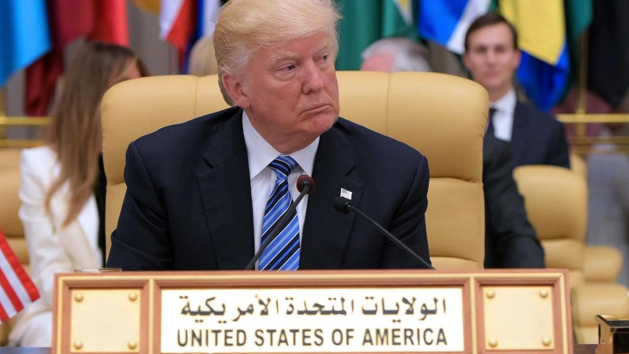 US-Präsident sitzt Donald Trump beim Gipfeltreffen muslimischer Staaten in Riad vor einer Reihe von Fahnen. Vor ihm ein Schild mnit der Aufschrift "United States of America" in arabischer und lateinischer Schrift.