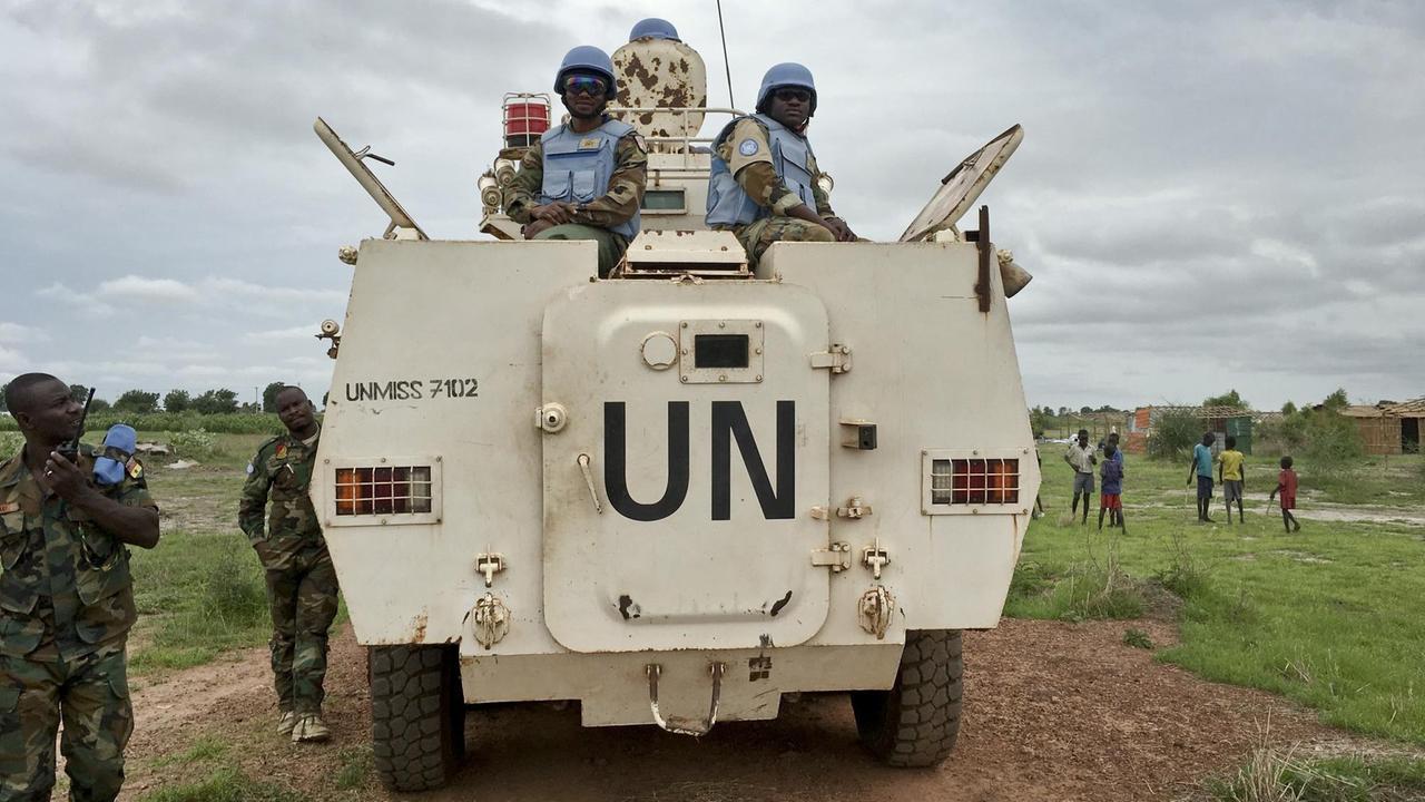 Blauhelmsoldaten auf einem weißen gepanzerten Fahrzeug mit der Aufschrift UN.