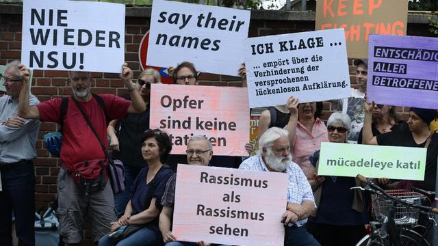 Mit Plakaten erinnerten Teilnehmer einer Schweigeminute an den 15. Jahrestag des NSU-Nagelbombenanschlags in Köln.