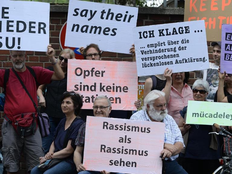 Mit Plakaten erinnerten Teilnehmer einer Schweigeminute an den 15. Jahrestag des NSU-Nagelbombenanschlags in Köln.