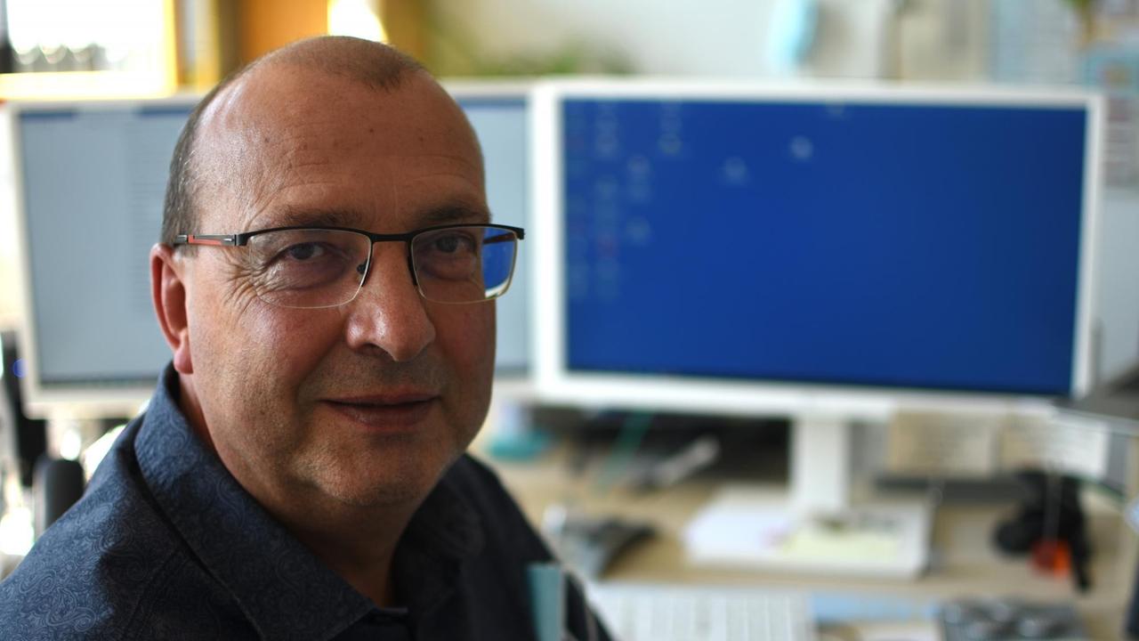 Jörg Heusler, Leiter des Gesundheitsamts Vorpommern-Rügen, sitzt vor seinem Schreibtisch mit zwei Monitoren Jörg Heusler, Leiter des Gesundheitsamts Vorpommern-Rügen, sitzt vor seinem Schreibtisch mit zwei Monitoren