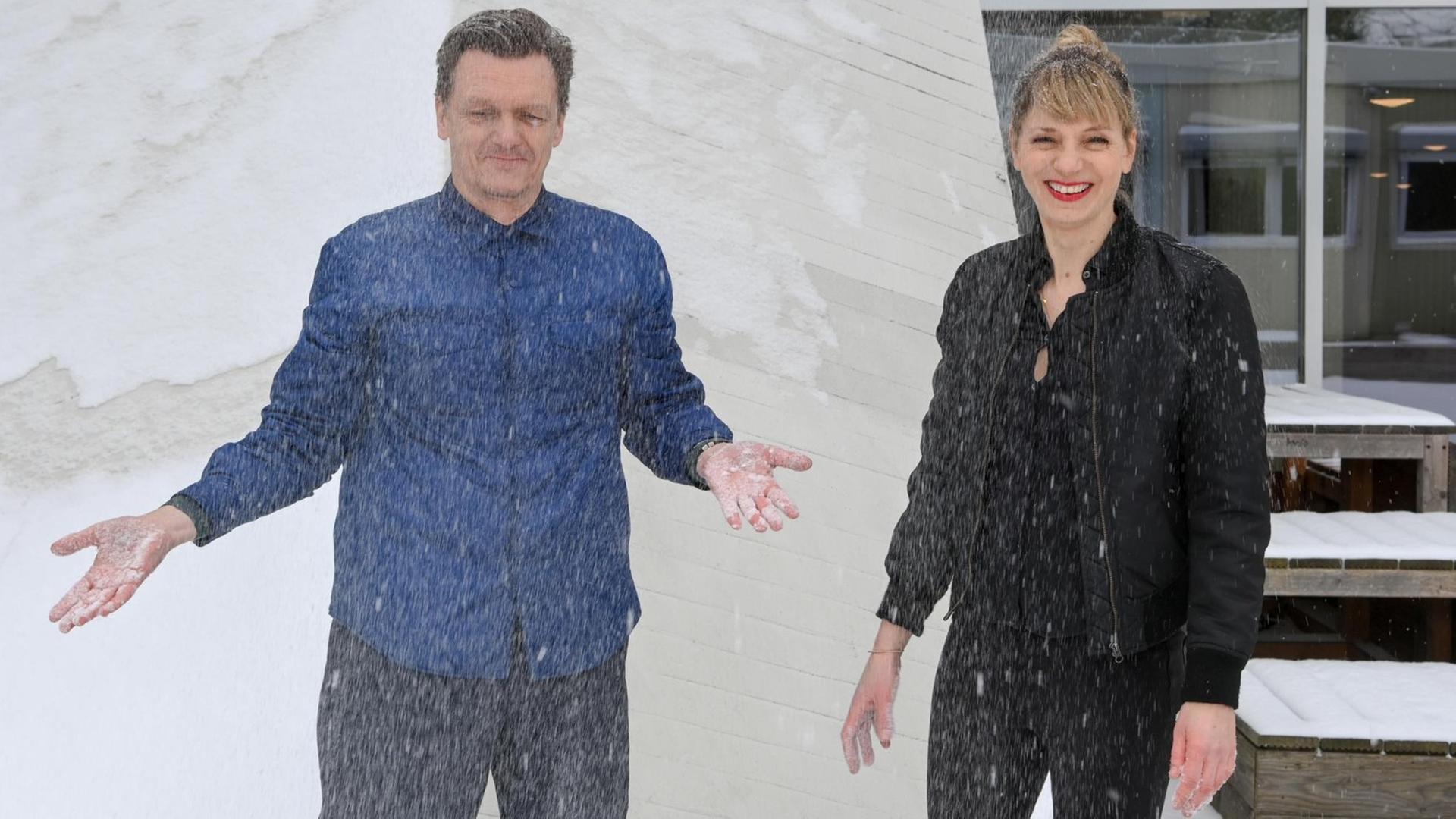 Thomas Oberender, Intendant der Berliner Festspiele, und Yvonne Büdenhölzer, Leiterin des Theatertreffens, stehen im Schnee vor dem Haus der Kulturen der Welt.
