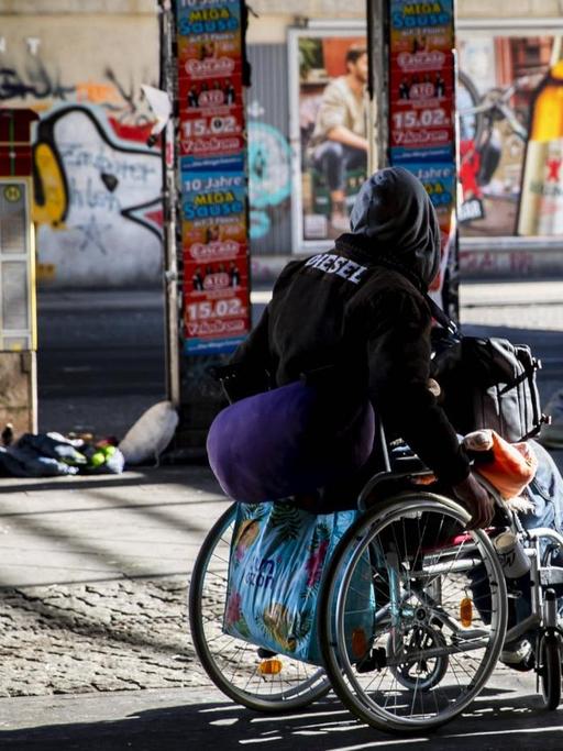 Ein einsamer Obdachloser auf dem Rollstuhl am Alexanderplatz in Berlin.