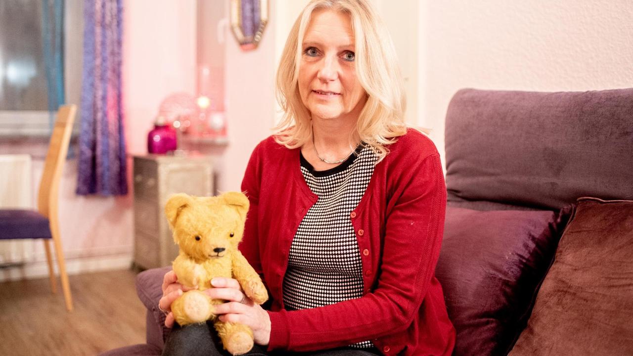 Porträt von Sabine Schwemm mit einem Teddybär aus ihrer Kindheit.