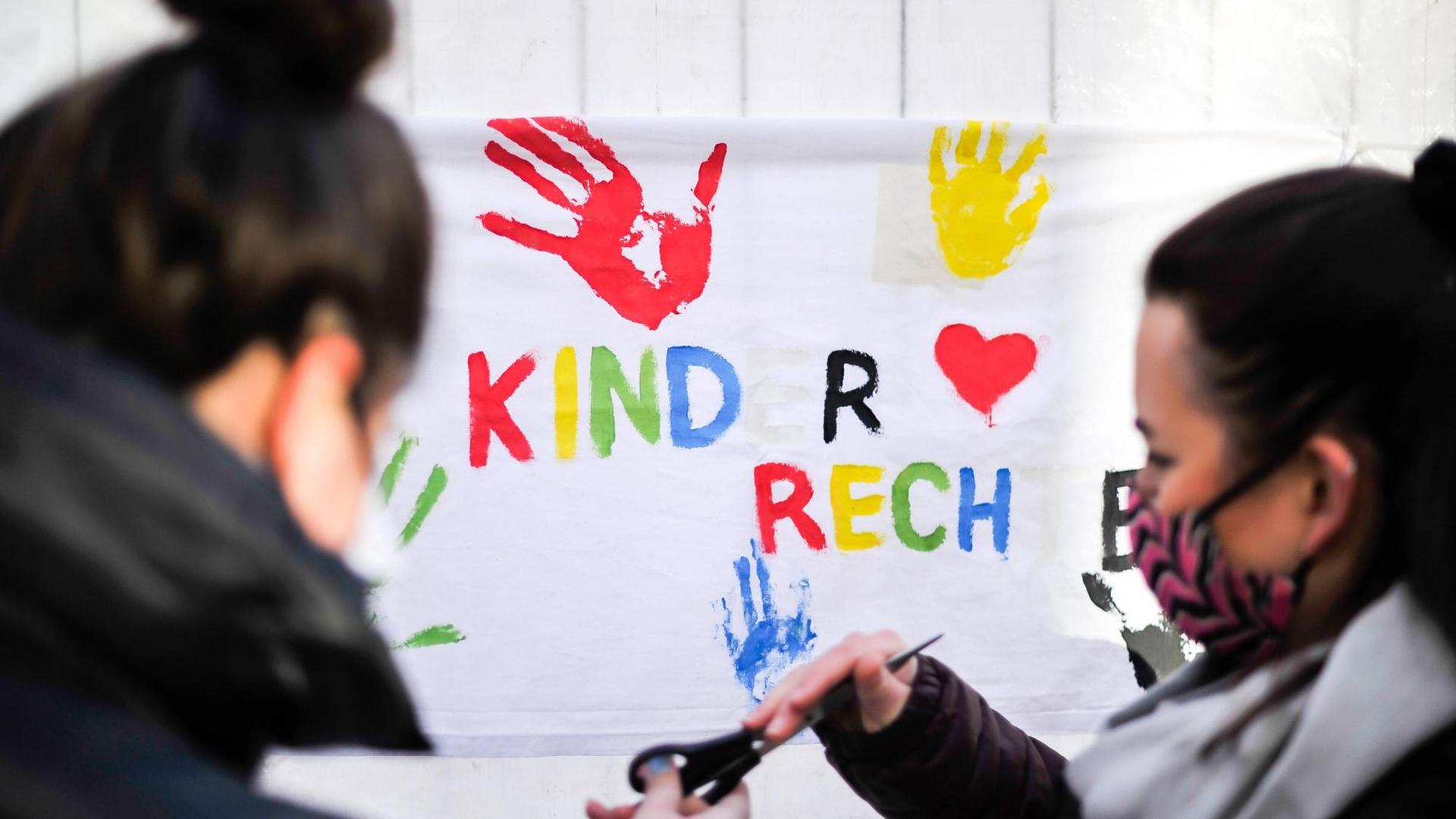 Zwei Mädchen bemalen ein Transparent mit der Aufschrift "Kinderrechte". Zwei Mädchen bemalen ein Transparent mit der Aufschrift "Kinderrechte".