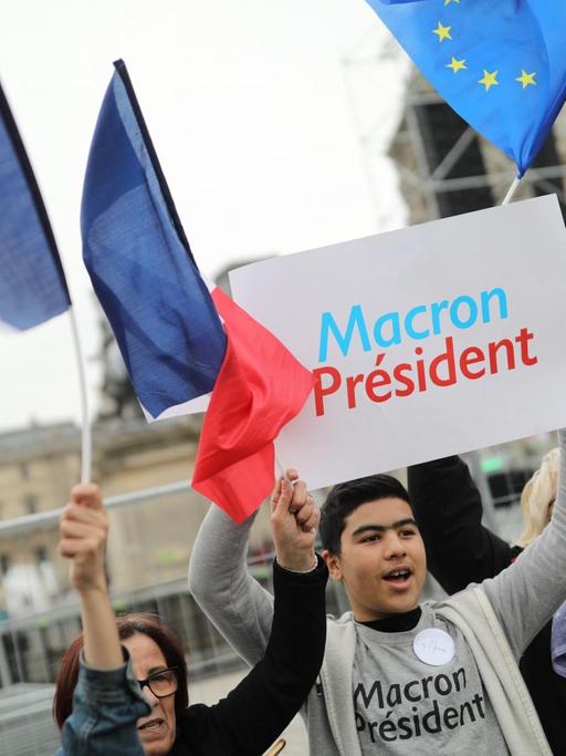 Ein Anhänger des sozialliberalen Kandidaten Macron hält am 07.05.2017 am Louvre in Paris ein Schild mit "Macron President" in die Höhe. Macron tritt in der Stichwahl um das Präsidentenamt in Frankreich gegen Le Pen von der Front National an.