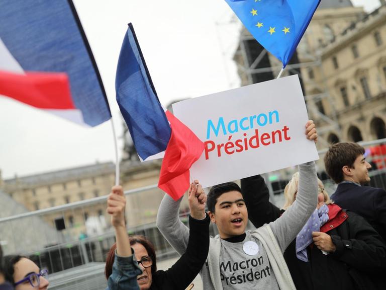 Ein Anhänger des sozialliberalen Kandidaten Macron hält am 07.05.2017 am Louvre in Paris ein Schild mit "Macron President" in die Höhe. Macron tritt in der Stichwahl um das Präsidentenamt in Frankreich gegen Le Pen von der Front National an.
